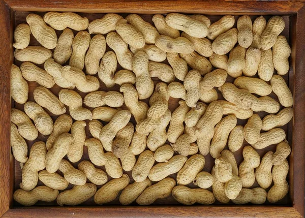 Top view of roasted peanuts poured on wooden tray copy space