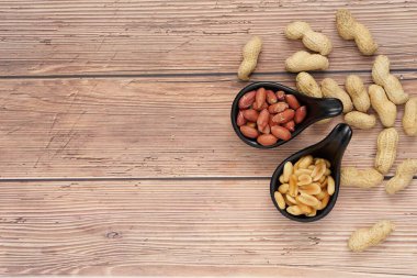 Kavrulmuş fıstık ve siyah seramik kaptaki fıstık tohumlarının yarısı ahşap..