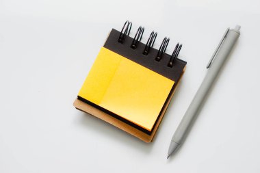 Boş turuncu not defteri ve beyaz arkaplanda gri kalem..