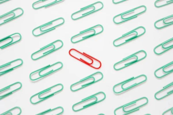 The red paper clip among the green paper clips placed in the opposite direction, Conceptual differentiation and smart business solution.
