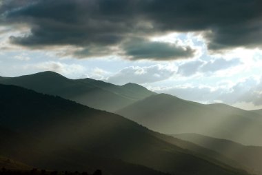 Güneş ışığı altında bulutlar ile akşam gökyüzü altında Dağ manzara.