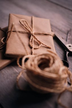 Tahta kırsal masa üzerinde bir paket Kraft kağıdı, ip ve makas.