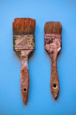 Yukarıdan görülen mavi arkaplanlı eski kullanılmış boya fırçaları