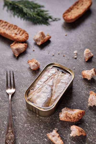 Tin can of sardines and pieces of toast in vertical