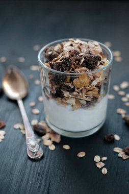 Kepekli müsli, kuru üzümlü ve yoğurtlu cam yakın plan.