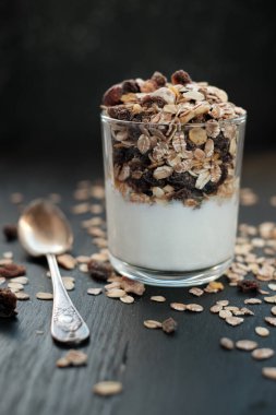 Kepekli müsli, kuru üzümlü ve yoğurtlu cam yakın plan.