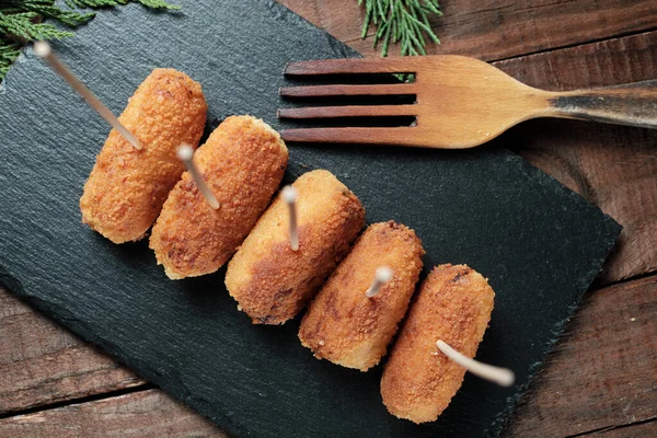 Siyah tahtada kürdanla delinmiş tavuk kroketleri.