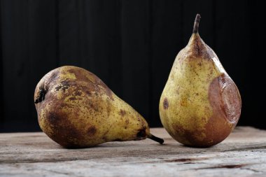 Kırsal masada, tüketim için kötü durumda iki çürük armut.