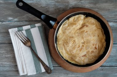 İspanyol tortillası tavanın içinde, ahşap masada.