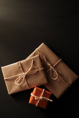 Kraft kağıdında siyah arkaplanlı ve iple bağlanmış hediye paketleri