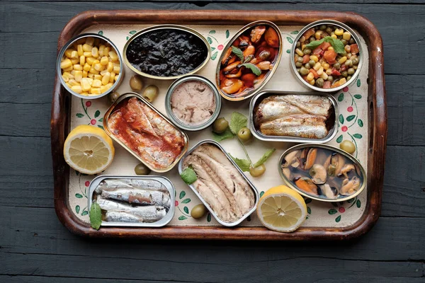 Variety of canned food cans on decorative wooden tray