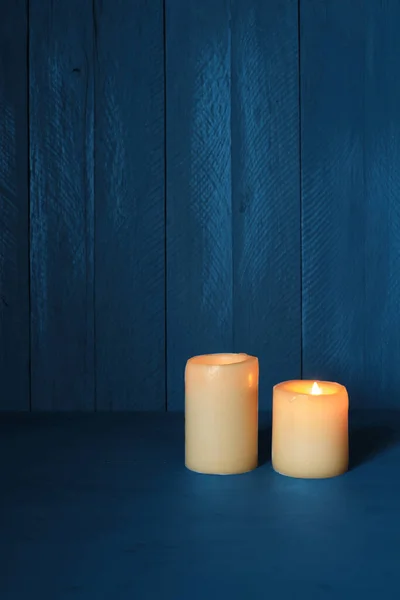 Mavi ahşap arka planı olan iki mum.