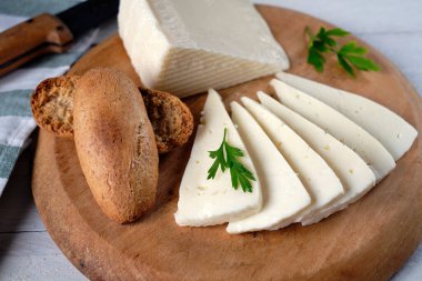 Yumuşak inek peyniri dilimleri ve tahtanın üzerinde kızarmış ekmek.