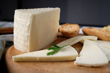 Yumuşak inek peyniri dilimleri ve tahtanın üzerinde kızarmış ekmek.