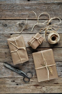 Kravat kağıdıyla sarılmış hediye paketleri ve kırsal ahşap masa üzerinde iple bağlanmış.