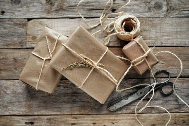 Kravat kağıdıyla sarılmış hediye paketleri ve kırsal ahşap masa üzerinde iple bağlanmış.