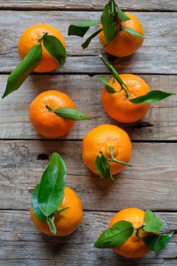 Kaba ahşap arka planda yukarıdan yaprakları olan mandalinalar