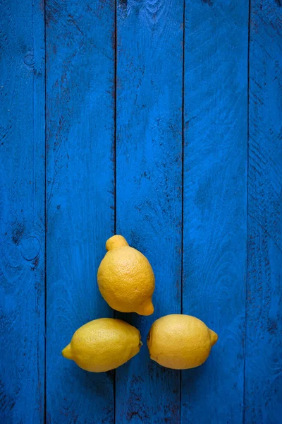 Three tasty lemons with blue wooden background
