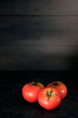 Siyah kırsal arka planda üç olgun domates.