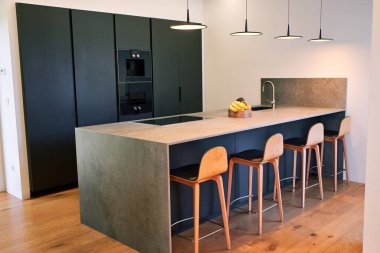 Tezgahı, sandalyeleri ve siyah dolabı olan modern mutfak.