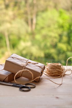 Tahta masa ve orman arka planında Kraft kağıdına sarılı hediye paketleri