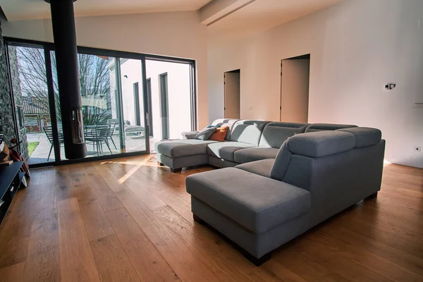 Kanepesi, geniş pencereleri ve güneşli bir günü olan modern oturma odası.