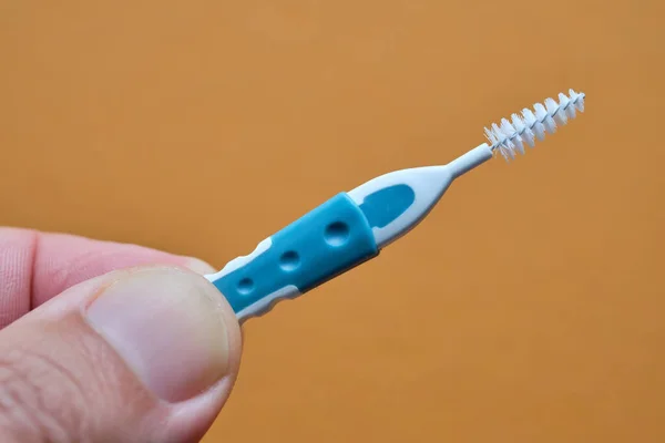 Turuncu arka planda parmakları olan interdental fırça