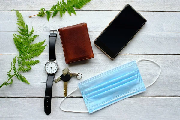 Operating room mask, keys, watch, smartphone and wallet on wooden table