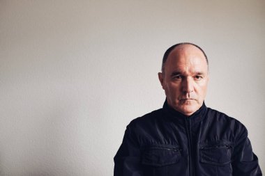 Ciddi orta yaşlı bir adam kameraya bakıyor.