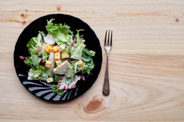 Siyah tabakta sağlıklı sezar salatası ve kırsal ahşap masa.