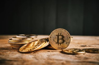 Tahta bir yüzey boyunca uzanan altın sikke koleksiyonu, önemli bir Bitcoin madeni para ile kripto para biriminin değerini vurguluyor..