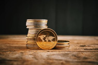 Tahta bir yüzey boyunca bir altın koleksiyonu yayılır, odak noktası olarak belirgin bir Litecoin madeni para, kripto para değerini vurgulayan.