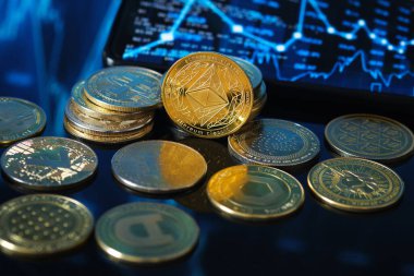 Golden Ethereum, akıllı telefon ekranında sergilenen ve dijital para birimi piyasa faaliyetlerini gösteren bir ticaret grafiğiyle çeşitli kripto para birimlerinin arasında bulunuyor..