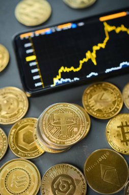 Piyasa eğilimlerini vurgulayan yükselen bir fiyat tablosu gösteren mobil bir cihazla çeşitli kripto para birimleri düzenlenmiştir. Bağlar aralarında belirgin bir şekilde yer alır..
