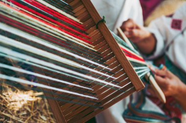 Geleneksel, renkli, yerli bir Sırp gibi giyinen kadın, ulusal desenli bir halı örüyor.