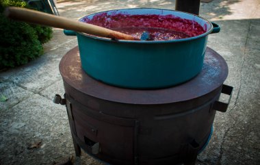 Geleneksel şekilde erik reçeli yapmak. Odun ocağında meyveler büyük tencerede pişiyor.