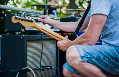 Sahnede canlı performans sergileyen bir müzisyen gitar çalıyor.