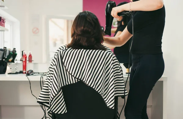 Hairdresser cutting long hair with professional scissors in hairdressing salon. Close up haircutter making woman haircut with scissors in beauty salon