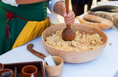 Ortaçağ kıyafetleri giymiş ve eski tariflere göre ortaçağ yemekleri hazırlayan bir kadının yakın çekimi.