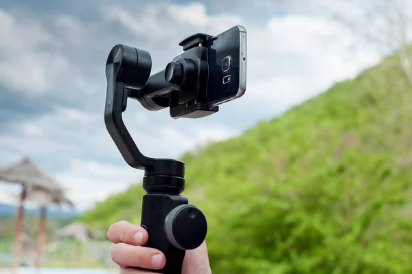Close-up of man shoots video on phone using an image stabilizer