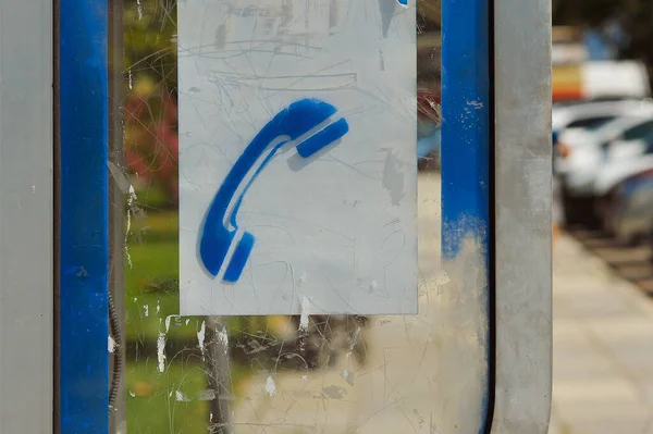 Close-up shows the blue telephone icon on the side glass of the booth