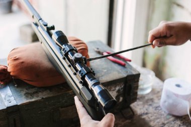 Silahçı, hava tüfeğinin optik görüşünü ayarlar. Keskin nişancı tüfeğini uzaktan ayarlıyorum.