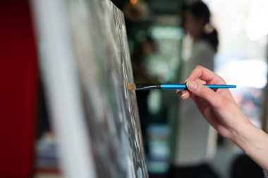 Fırça ve palete yakın çekim. Resim stüdyosunda fırça tutan kız..