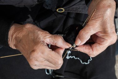 Yaşlı kadın çorap örüyor. Yaşlı büyükanne parkta dinleniyor, yeni doğan torun ailesi için örgü örüyor.