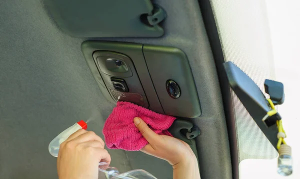 A woman is disinfecting her car with a pink wipe. Prevent the virus and bacterias, Prevent covid19, corona virus, Alcohol Sanitizer. Hygiene concept at home.