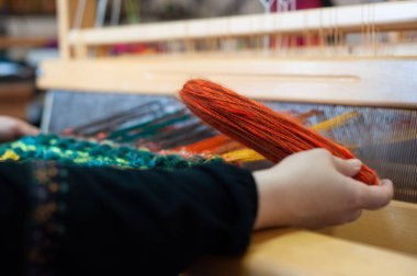 Geleneksel yün ipliklerle örülmüş atkı yapan beyaz bir kadının ellerine yaklaş. Kumaş sanatı ve el işi konsepti ev yapımı.