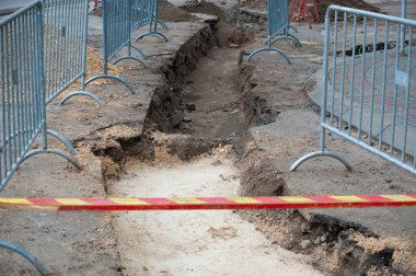 Şehir caddesinin yeniden inşası. Atmosferik kanalizasyon düzeni. Eski kanalizasyon borularının değiştirilmesi nedeniyle sokağın kazılan kısmında koruma çiti ve uyarı işaretleri var..