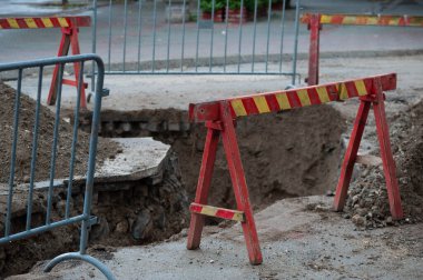 Şehir caddesinin yeniden inşası. Atmosferik kanalizasyon düzeni. Eski kanalizasyon borularının değiştirilmesi nedeniyle sokağın kazılan kısmında koruma çiti ve uyarı işaretleri var..