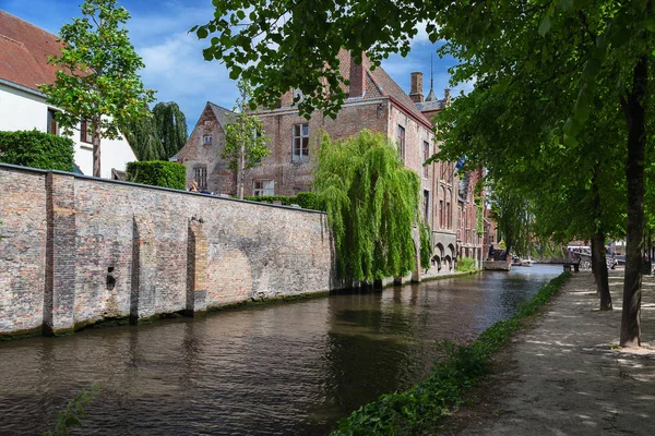 Bruges, Belçika'daki kanal kıyısında antik evler. Bir tuğla ve kiremit çatılar ile bir taş evlerden. Yaz güneşli bir gün, kanalın su yansıma.