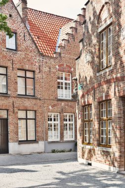 Bruges, Belçika - 8 Haziran 2017: Avrupa antik kentin dar sokak. Tuğla evler, gri kaldırım taşı döşeli yolu. Güneşli yaz günü, bu renkli